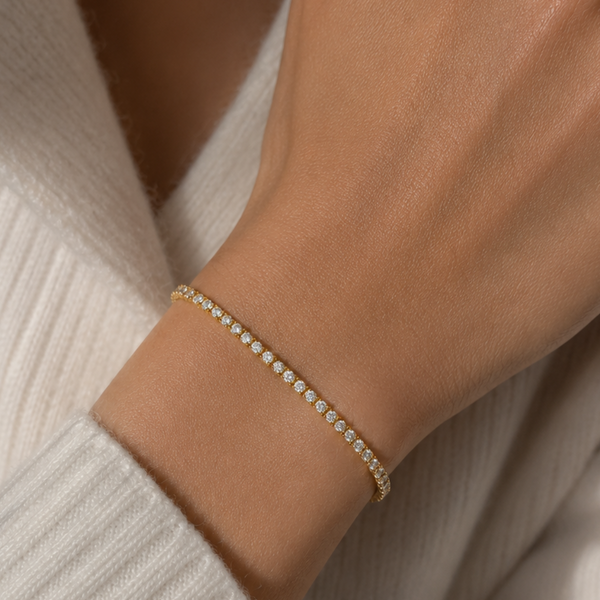 Woman wearing a 3mm gold tennis bracelet with round cubic zirconia stones.