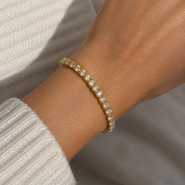 Woman wearing a 5mm gold tennis bracelet set with sparkling cubic zirconia stones.